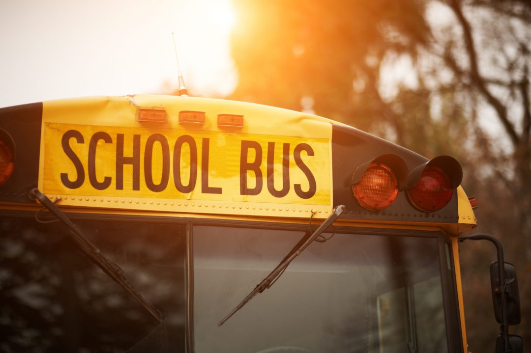 Front closeup view of yellow school bus windshield sign at sunset